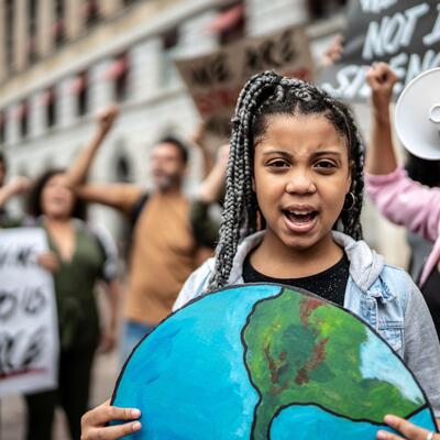 A young protestor holds up artwork of the Earth