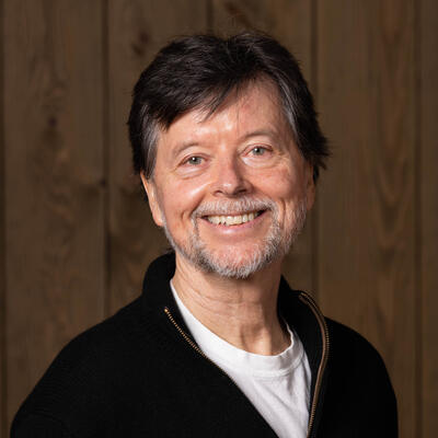 man smiling at camera in front of wood background