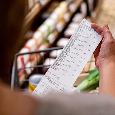 A woman holds her receipt over her grocery cart