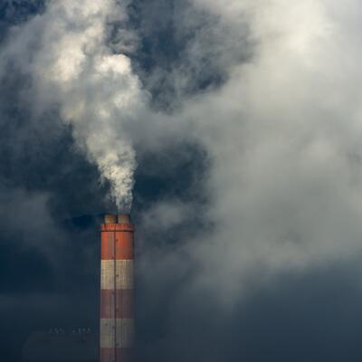 A smokestack belches into a darkened sky
