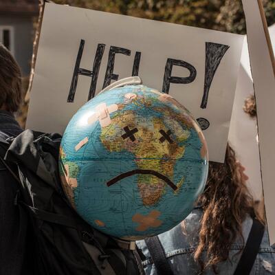A protestor wears a globe with a frowning face on his back