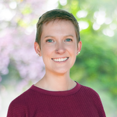 Headshot for Rachael Lacey - white woman with short blond hair wearing a maroon shirt