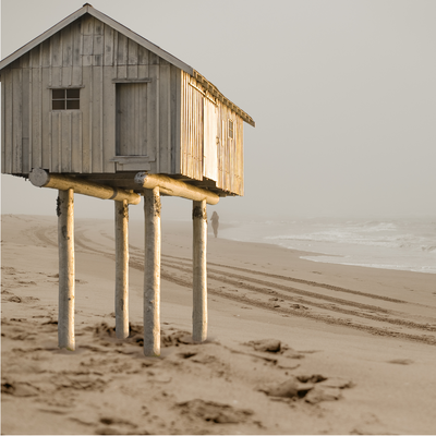 Small house on stilts standing alone on a cloudy beach