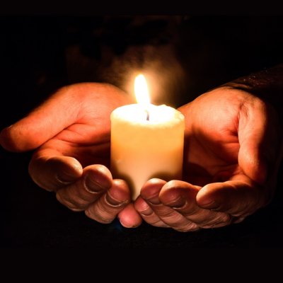 open hands holding a candle 