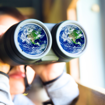 woman looking through a pair of binoculars; in each lens is an image of the earth