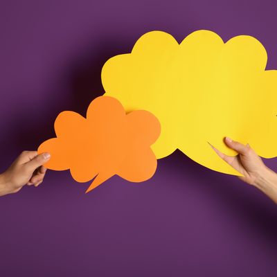 two hands holding paper cutouts of speech bubbles