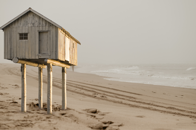 Small house on stilts standing alone on a cloudy beach